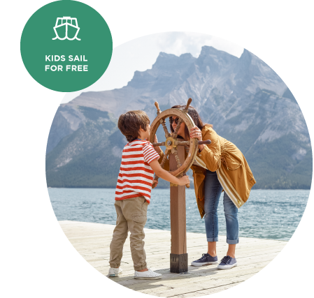 A child and mother look through a wooden boat steering wheel mountain on a lakeside dock